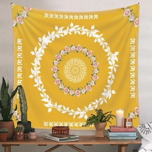 Detail of yellow mandala tapestry with pink roses hanging over a wooden desk