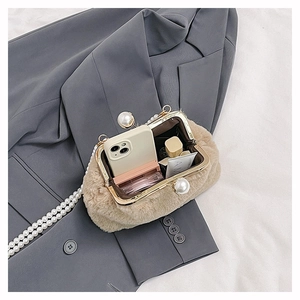 Detail view of beige plush handbag with large pearl clasps and golden metal frame