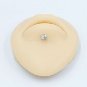 Vue détaillée d'un piercing de nombril papillon argenté avec une pierre rose sur modèle
