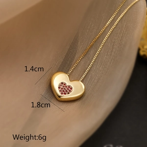 Macro detail of 18K gold plated heart pendant with red zircon and size specifications