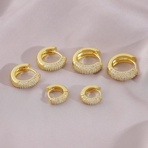 Three pairs of gold-plated hoop earrings with pave-set cubic zirconia on silk background
