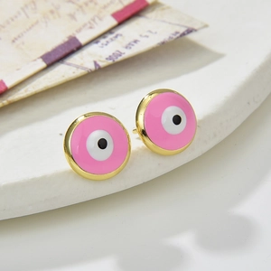 Pink evil eye stud earrings in round gold base displayed on white ceramic tray