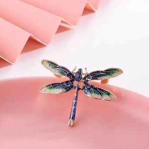 Detailed view of a dragonfly brooch with blue enamel wings and a centered blue crystal
