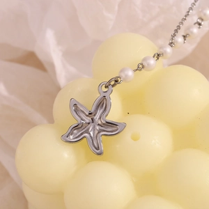 Detailed close-up of a silver starfish pendant and white pearl chain necklace