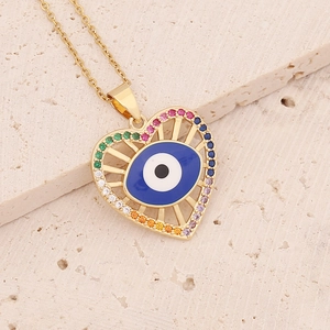 Detail shot of heart-shaped necklace with blue eye and colorful stones on stone base