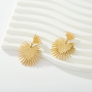 Detailed view of sunburst earrings in 18K gold plated stainless steel on white pedestal