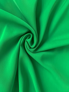 Close-up of bright green fabric with smooth texture and silk-like glossy finish