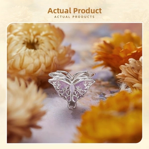 Detailed macro view of silver butterfly charm with purple enamel and marquise gemstone