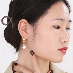 Détail de boucles d'oreilles franges dorées 18k avec perles sur un mannequin