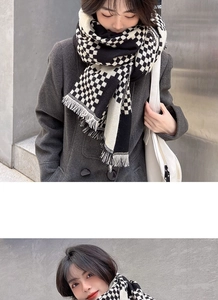 Close-up of black and white plaid knit scarf featuring soft fringe and classic pattern