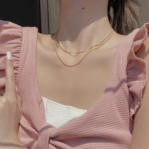 Detailed close-up of a stylish double-layered golden bead necklace worn by a female model