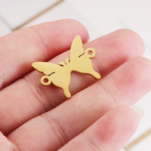 Polished golden butterfly stainless steel charm held by hand for jewelry DIY