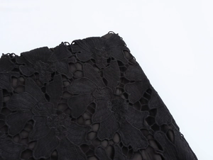 Dettaglio del tessuto in pizzo nero con intricati motivi floreali traforati e trama