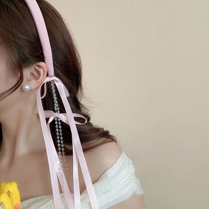 Close-up of pink fabric headband with bow and crystal tassel on a fashion model