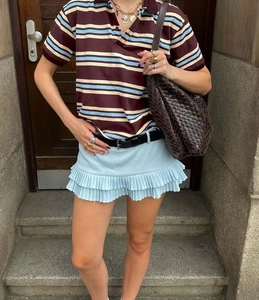 Détail d'un polo à rayures assorti à une jupe bleue à volants et un sac à bandoulière