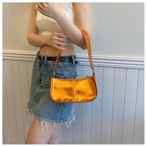 Close-up of metallic orange shoulder bag with silver rivets and mirror finish texture