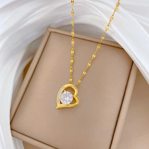 Close-up of golden heart pendant with crystal inlays inside a beige jewelry box