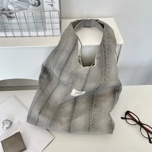 Tie-dye grey denim tote bag with white square label displayed with lifestyle accessories