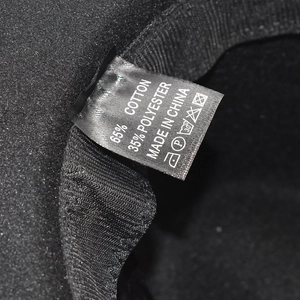 Detail de l'etiquette de lavage montrant 65% coton et 35% polyester sur le chapeau noir