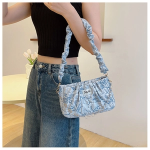 Light blue pleated shoulder bag with metal chain detail shown on a female model