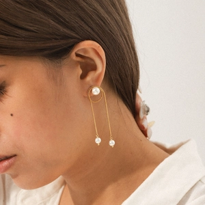Close-up of gold stainless steel snake chain tassel earrings with three pearl accents on model