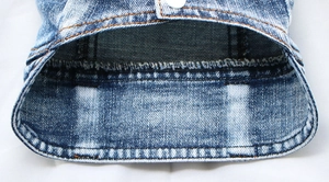 Detail of denim pet vest showing light blue washed fabric and reinforced amber stitching