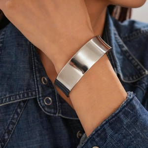 Close-up of polished silver wide cuff bracelet paired with dark blue denim jacket