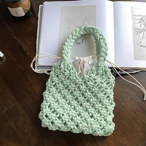 Handmade woven mint green tote bag with drawstring lining on a dark wood table