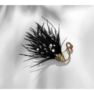 Macro view of black swan brooch with feathers, faux pearls and golden metal details