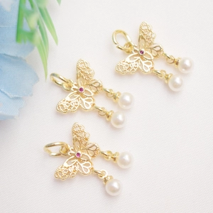 Detailed macro view of 14K gold butterfly pendant with white pearls and pink gemstone
