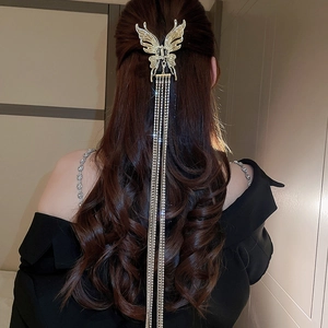 Vue détaillée d'une pince à cheveux papillon dorée avec de longs glands en strass