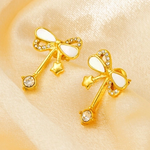 Gold-plated bow earrings with white enamel stars and crystals on satin background