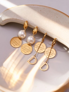 Détail de boucles d'oreilles plaquées or 18 carats avec perles et breloques lettre D sur céramique