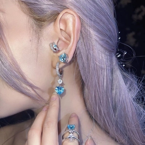 Détail de boucles d'oreilles cœur en zircon et bague sertie de cristaux bleus