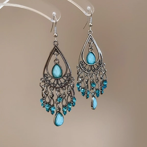 Detailed close-up of vintage silver earrings with blue teardrop stones and bead tassels