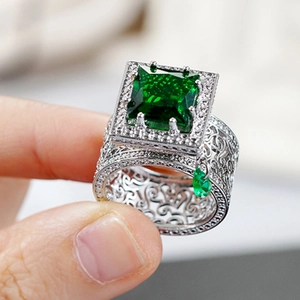 Detail of emerald-cut green stone ring with hollow floral band and drop pendant