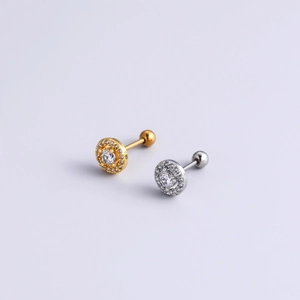 Close-up of gold and silver screw-back cartilage earrings with sparkling zircon halo design