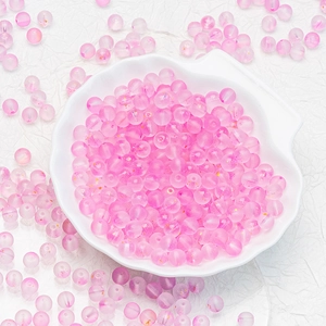 Macro shot of 6mm pink frosted glass beads with glitter in a white shell dish for DIY jewelry