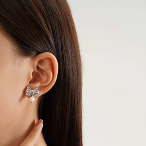 Elegant titanium steel bow stud earring with a round white pearl on a female model