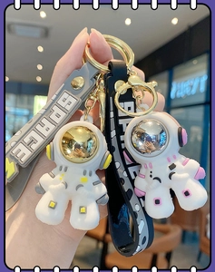 Close-up of gold and silver space astronaut keychains with SPACE silicone straps