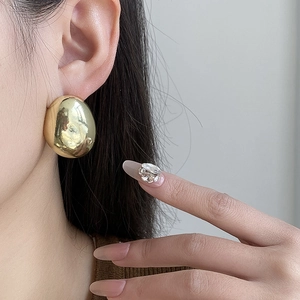 Close-up of polished gold teardrop earrings worn by a model for a minimalist luxury look