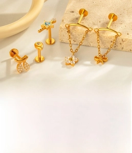 Detailed view of titanium gold piercing jewelry with star and floral zircon inlays