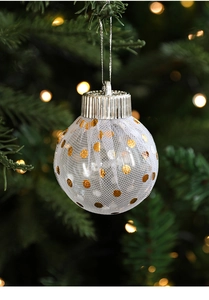 White tulle Christmas ball with gold polka dots hanging on a festive pine tree branch