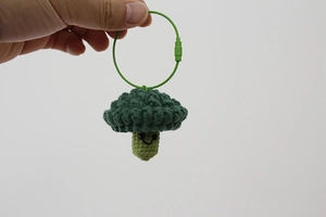 Detailed view of a handmade crochet broccoli pendant with a green metal wire ring