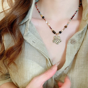 Detail of colorful resin beaded necklace featuring a vintage hollow metal flower pendant