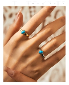 Detail showing two gold and silver rings with oval blue opal stones on a model hand