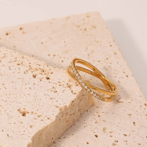 Elegant gold-tone criss-cross ring with micro-pave crystals on a textured stone base