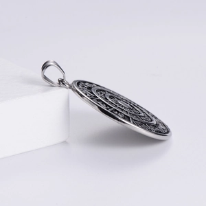 Detailed view of vintage silver Viking pendant with zodiac sun runes on white stand