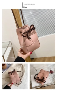 Detail of pink hand-woven bucket bag with brown drawstring bow and crossbody strap