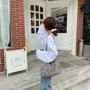 Detailed back view of a large leopard print canvas tote bag carried by a model outdoors